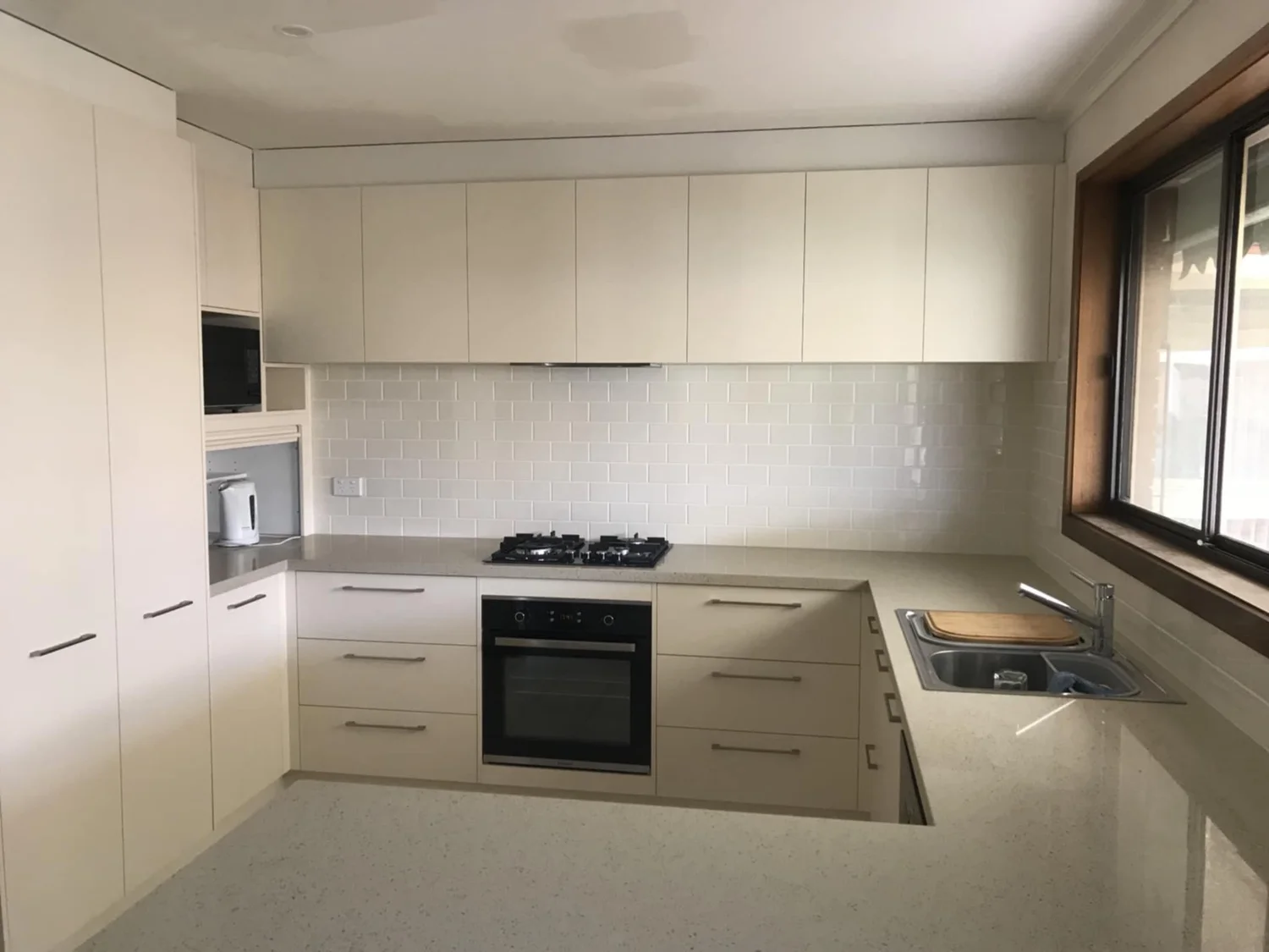 Renovated kitchen with white cabinetry and new benchtops
